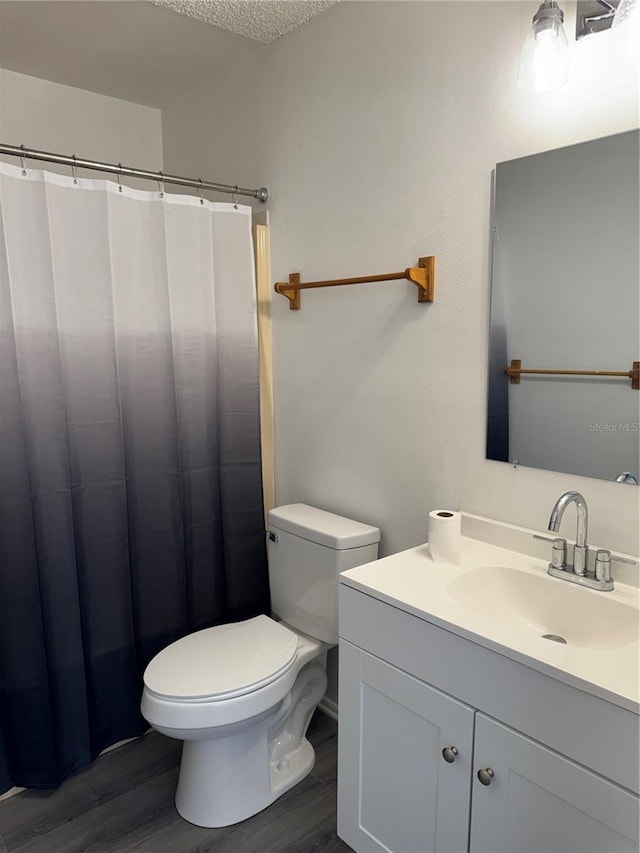 full bathroom with a shower with curtain, toilet, a textured ceiling, wood finished floors, and vanity