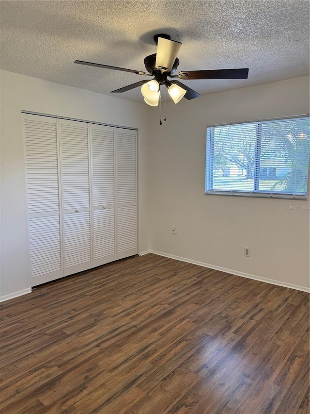 unfurnished bedroom with a closet, a textured ceiling, a ceiling fan, and dark wood-style flooring