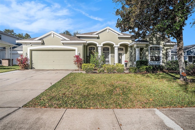 view of front of property featuring stucco siding, driveway, an attached garage, and a front lawn