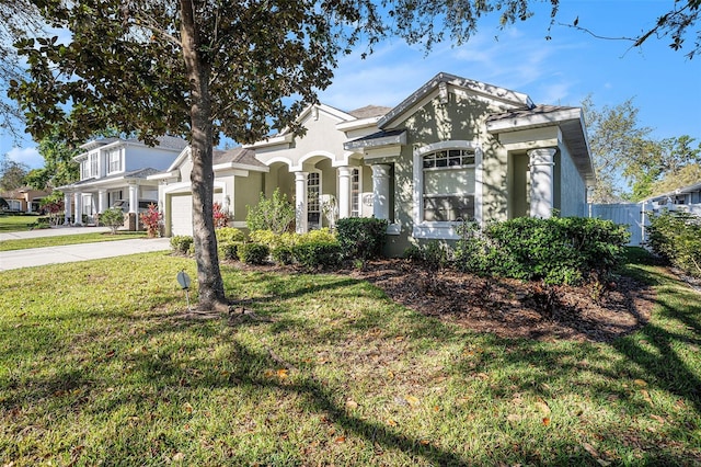 view of front of house with stucco siding, a front yard, concrete driveway, and an attached garage