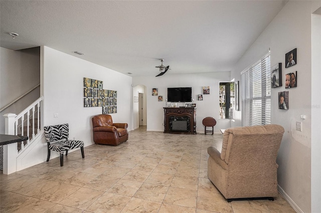 living area featuring visible vents, a ceiling fan, a fireplace, baseboards, and stairs