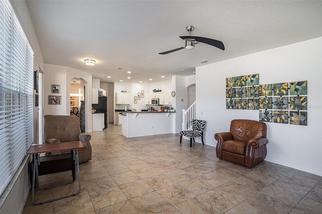 living area featuring a textured ceiling, recessed lighting, arched walkways, ceiling fan, and stairs