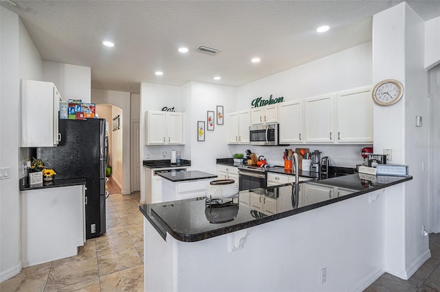 kitchen featuring visible vents, a peninsula, arched walkways, white cabinets, and appliances with stainless steel finishes