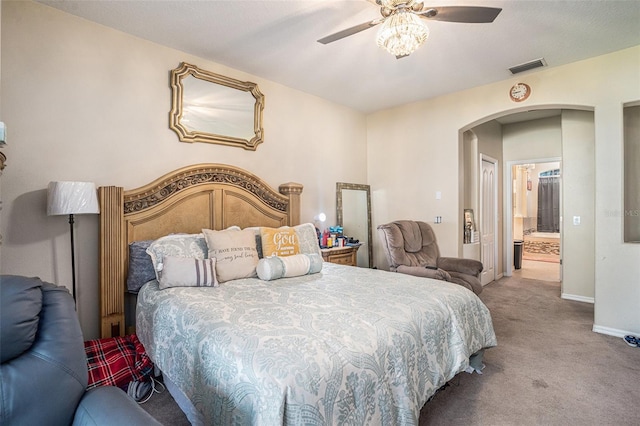 carpeted bedroom with visible vents, arched walkways, baseboards, and ceiling fan