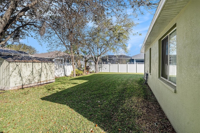 view of yard with an outbuilding, a storage unit, and a fenced backyard