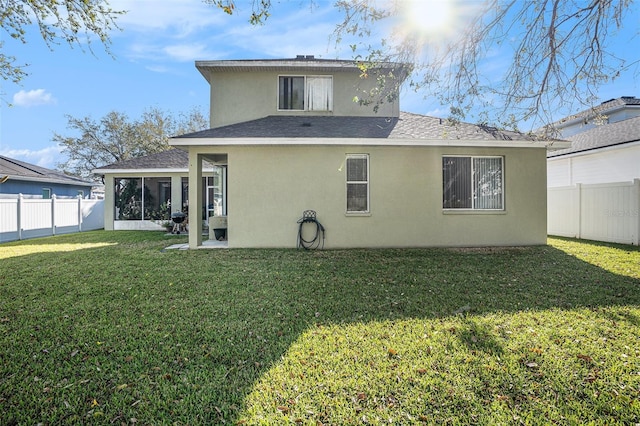 rear view of house with stucco siding, a lawn, a fenced backyard, roof with shingles, and a sunroom