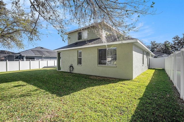 back of property featuring a yard, a fenced backyard, and stucco siding