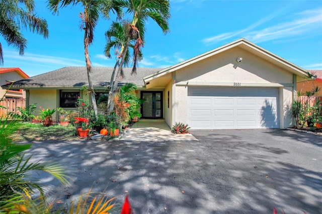 single story home featuring aphalt driveway, fence, a garage, and stucco siding