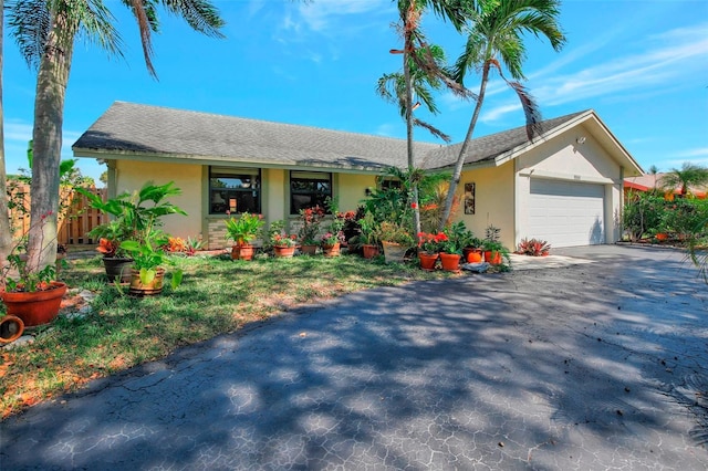 single story home featuring stucco siding, driveway, an attached garage, and fence