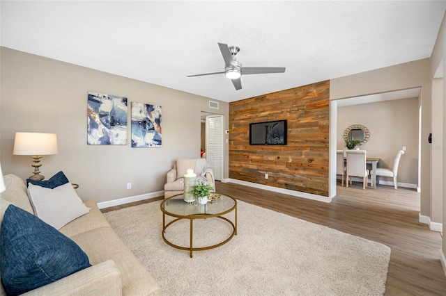 217 Emerald Ln, Largo, FL 33771 - living room with an accent wall, wood finished floors, wood walls, visible vents, and ceiling fan