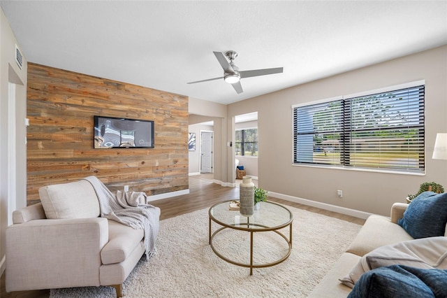 217 Emerald Ln, Largo, FL 33771 - living area with wood walls, an accent wall, visible vents, a ceiling fan, and wood finished floors