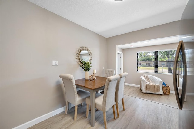 217 Emerald Ln, Largo, FL 33771 - dining area featuring baseboards, light wood-style floors, and a textured ceiling