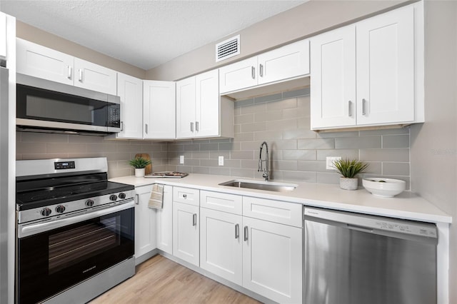 217 Emerald Ln, Largo, FL 33771 - kitchen with decorative backsplash, light countertops, stainless steel appliances, white cabinetry, and a sink