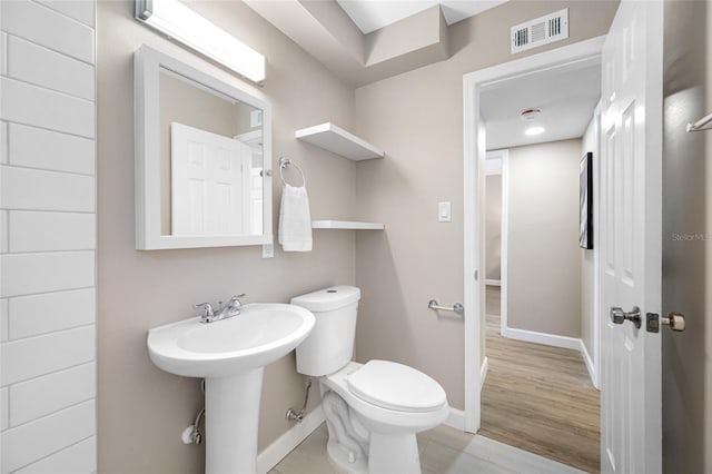 217 Emerald Ln, Largo, FL 33771 - half bathroom with visible vents, baseboards, toilet, wood finished floors, and a sink