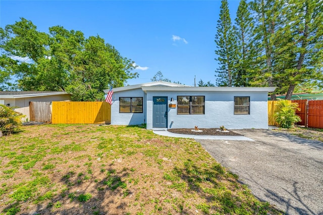 217 Emerald Ln, Largo, FL 33771 - view of front of home featuring stucco siding, aphalt driveway, fence, and a front lawn