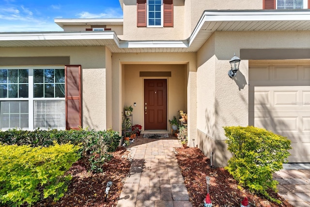 property entrance featuring a garage and stucco siding