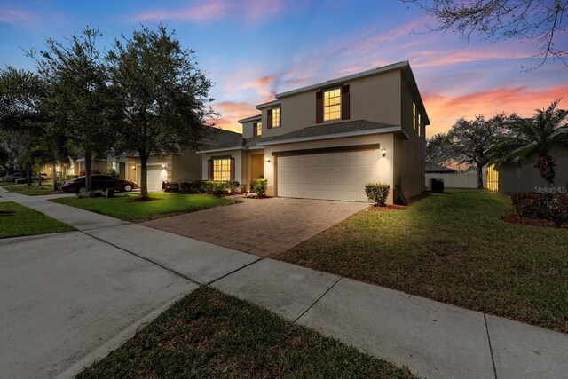 traditional-style house with a front yard, fence, stucco siding, a garage, and decorative driveway