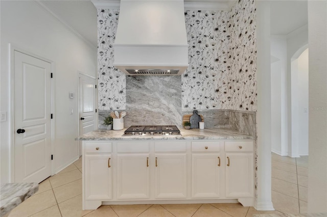 kitchen with premium range hood, backsplash, stainless steel gas stovetop, and crown molding