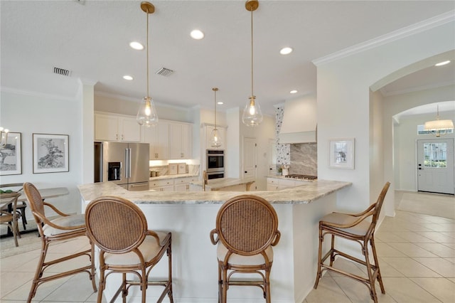 kitchen featuring light tile patterned floors, decorative backsplash, arched walkways, and appliances with stainless steel finishes