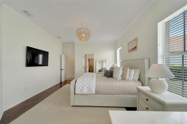 bedroom with visible vents, wood finished floors, baseboards, and ornamental molding