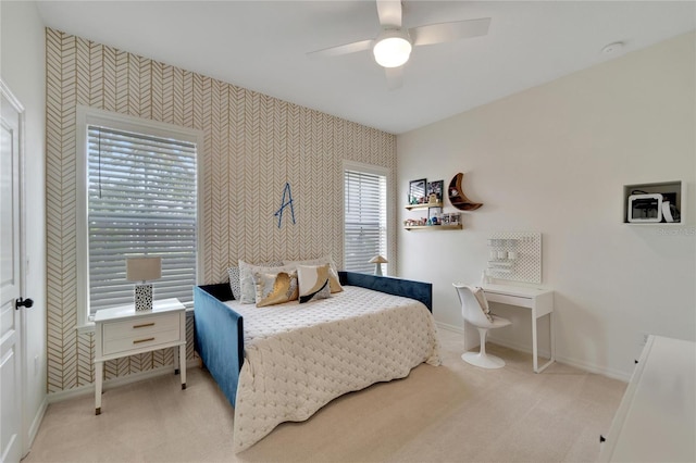 bedroom with wallpapered walls, light colored carpet, baseboards, and ceiling fan