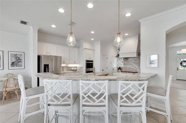 kitchen featuring premium range hood, visible vents, arched walkways, appliances with stainless steel finishes, and light tile patterned flooring