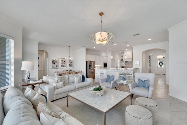 living area with visible vents, crown molding, light tile patterned floors, arched walkways, and a notable chandelier