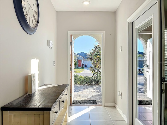 entryway with light tile patterned flooring, a healthy amount of sunlight, and baseboards