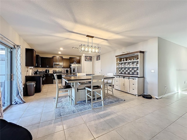 dining area featuring light tile patterned floors, a textured ceiling, and baseboards