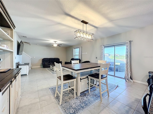 dining area with light tile patterned floors, baseboards, a textured ceiling, and a ceiling fan