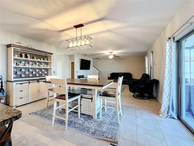 dining space with a textured ceiling, light tile patterned flooring, and a ceiling fan