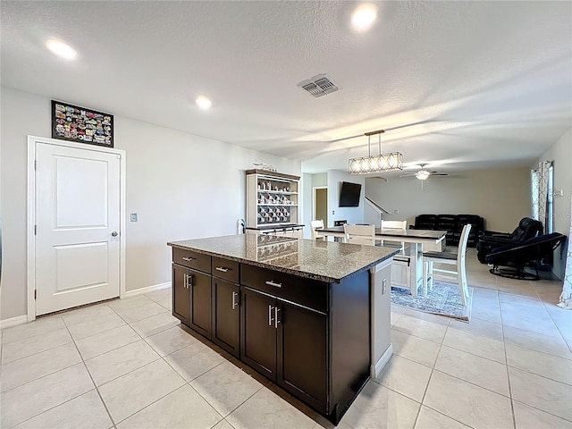 kitchen with light tile patterned floors, visible vents, ceiling fan, and a center island