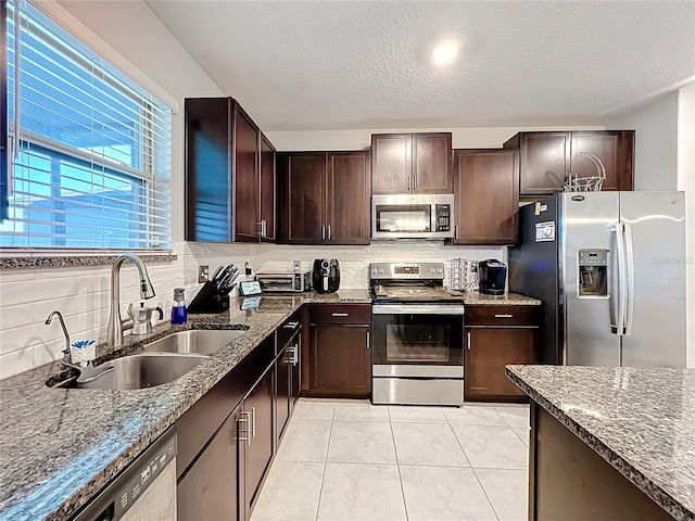 kitchen featuring a sink, dark stone counters, tasteful backsplash, and appliances with stainless steel finishes