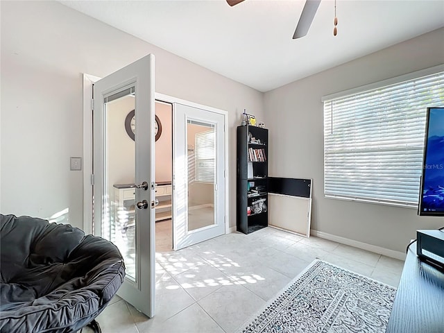 interior space with light tile patterned floors, french doors, baseboards, and a ceiling fan