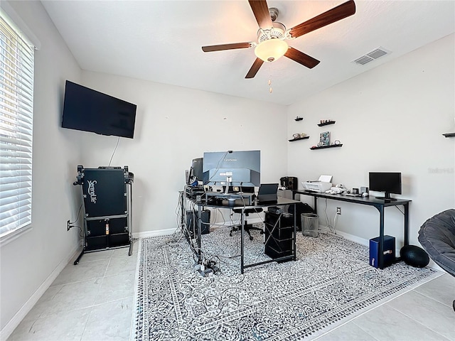 office area with tile patterned floors, visible vents, a healthy amount of sunlight, and a ceiling fan