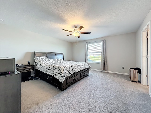 bedroom with light carpet, a textured ceiling, a ceiling fan, and baseboards