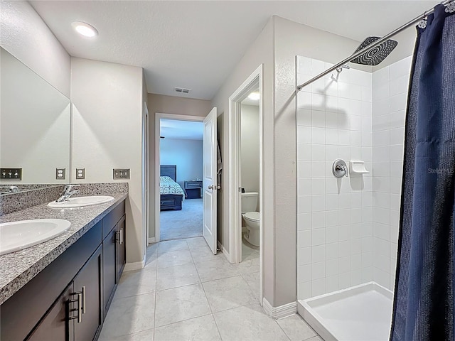 ensuite bathroom with a sink, toilet, a stall shower, and double vanity