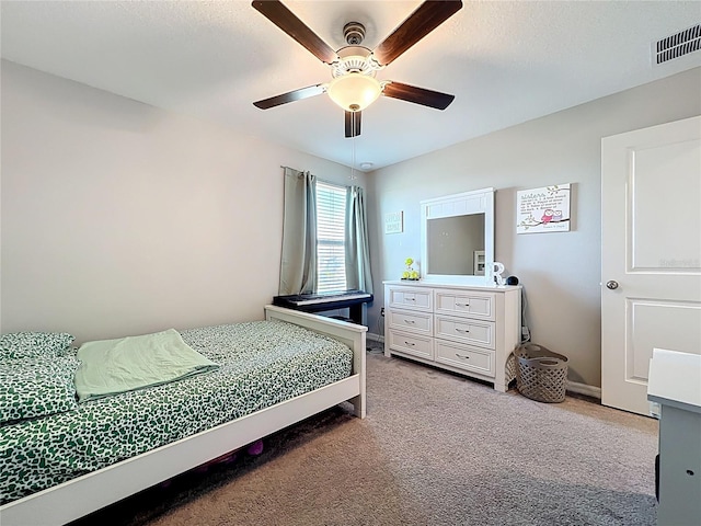 bedroom with a ceiling fan, light colored carpet, visible vents, and a textured ceiling