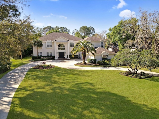 view of front facade featuring stucco siding, concrete driveway, and a front lawn