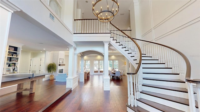 foyer featuring visible vents, stairway, an inviting chandelier, ornate columns, and wood-type flooring