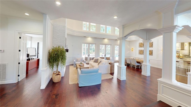 living room with visible vents, dark wood-type flooring, recessed lighting, arched walkways, and decorative columns