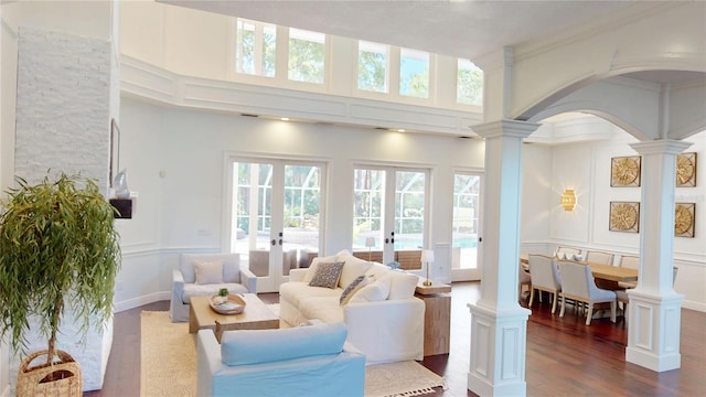 living room with a decorative wall, french doors, dark wood-type flooring, and decorative columns