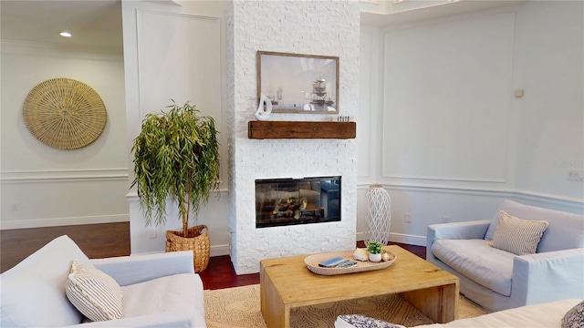 living area featuring a stone fireplace, recessed lighting, baseboards, and wood finished floors