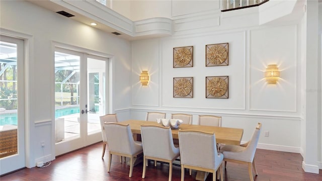 dining room featuring a decorative wall, a healthy amount of sunlight, and dark wood-type flooring