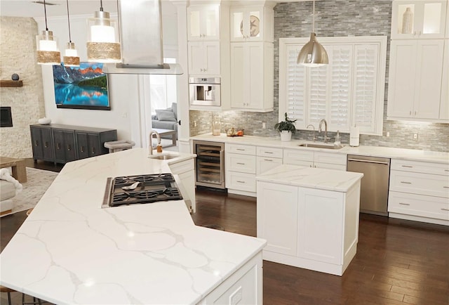 kitchen featuring a kitchen island with sink, a sink, stainless steel appliances, wine cooler, and decorative backsplash