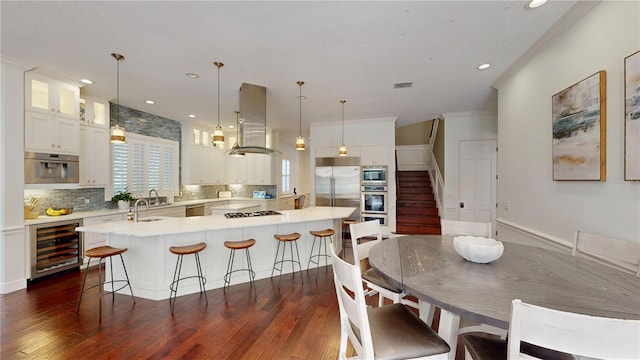 kitchen with ornamental molding, decorative backsplash, a large island, wine cooler, and island range hood