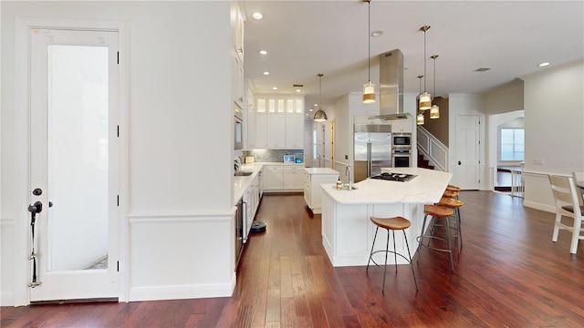 kitchen with white cabinetry, appliances with stainless steel finishes, island range hood, decorative backsplash, and dark wood-style flooring