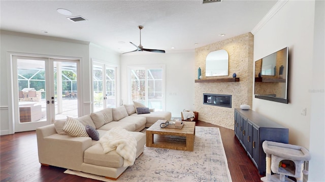 living area with visible vents, french doors, a fireplace, crown molding, and dark wood-style flooring