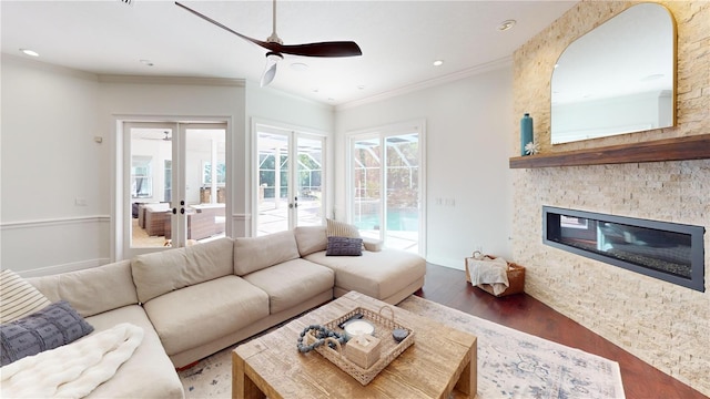 living room featuring wood finished floors, a fireplace, ceiling fan, french doors, and crown molding