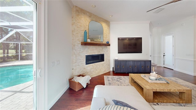 living area with visible vents, dark wood finished floors, a fireplace, crown molding, and baseboards